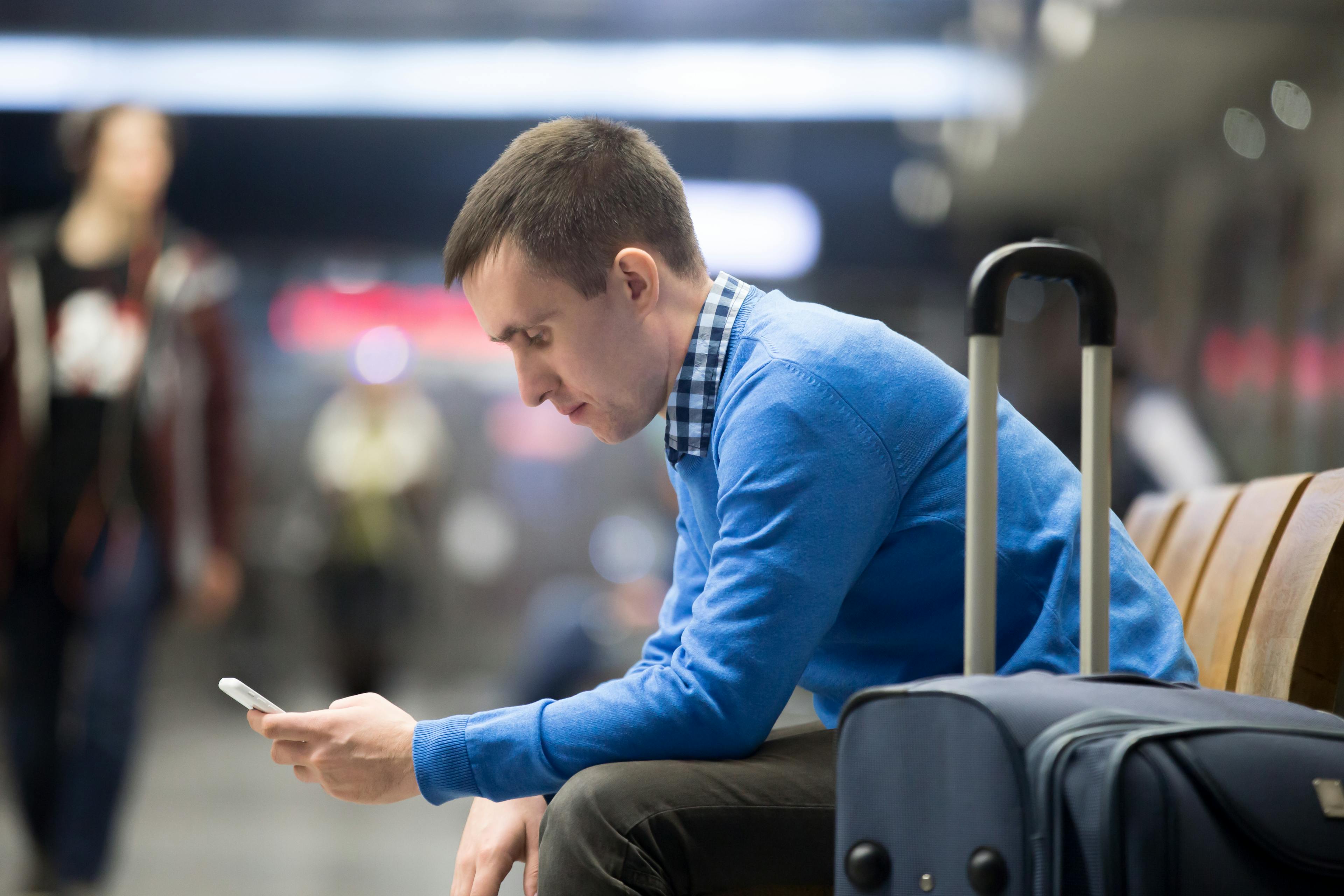 man at airport looking at his smartphone