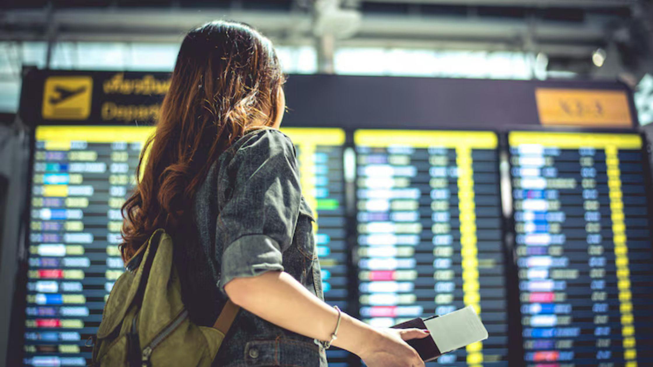 female tourist looking at flight schedule board